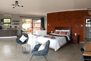 1 dormitorio con 1 cama grande y pared de ladrillo en Rocky Road Mountain Lodge en Pretoria