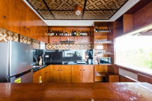 La cuisine est équipée d'armoires en bois et d'un réfrigérateur en acier inoxydable. dans l'établissement Bernis Hostel, à Moalboal