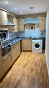 cocina con armarios de madera, lavadora y secadora en Two bedroom Entire Apartment in Roman road with Free Parking, en Middlesbrough