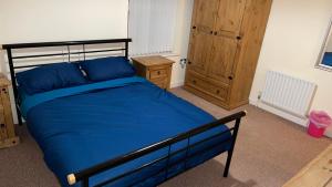 a bedroom with a blue bed and a wooden cabinet at Two bedroom Entire Apartment in Roman road with Free Parking in Middlesbrough