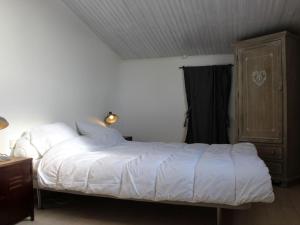 Schlafzimmer mit einem weißen Bett und einem Holzschrank in der Unterkunft Maison Saint-Georges-d'Oléron, 3 pièces, 4 personnes - FR-1-246A-85 in Saint-Georges-dʼOléron