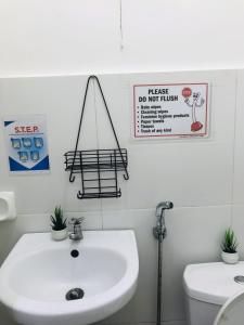 a bathroom with a sink and a toilet and signs at Queen's Room Rental 2 in El Nido