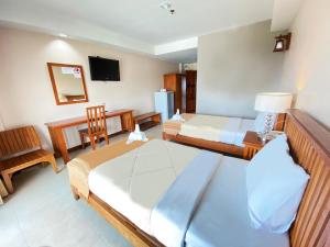 um quarto de hotel com duas camas e uma televisão em Maihom Resort Hotel em Nakhon Sawan