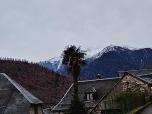 a palm tree next to a house with mountains in the background at Appartement Boutx 4 PERSONNES in Boutx