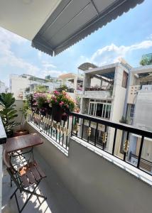 a balcony with a table and chairs and flowers at Song Anh Indochina Studios Nguyen Thai Binh in Ho Chi Minh City