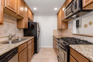 kuchnia z drewnianymi szafkami i czarną lodówką w obiekcie Luxury 2-Bedroom Condo in Studio City w Los Angeles