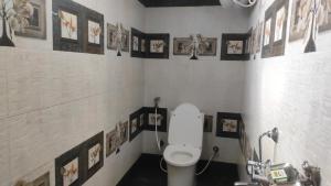 a bathroom with a toilet and pictures on the wall at Pears Garden Royal Suite in Kodaikānāl