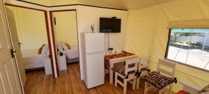 um pequeno quarto com uma pequena mesa e um frigorífico em Zonnevanger Guesthouse em Noorder-Paarl