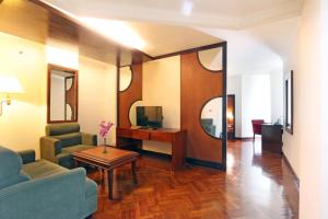 Hotel Kaisar في جاكرتا: غرفة معيشة مع أريكة وطاولة وتلفزيون