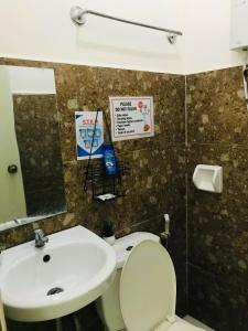 a bathroom with a sink and a toilet and a mirror at Queen's Room Rental 3 in El Nido
