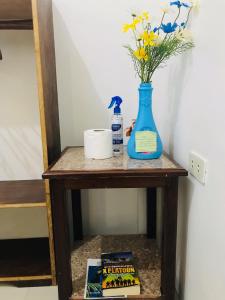 einen Tisch mit einer blauen Vase und einem Buch in der Unterkunft Queen's Room Rental 3 in El Nido
