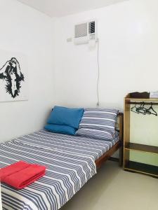 Schlafzimmer mit einem Bett mit blauen und weißen Streifen in der Unterkunft Queen's Room Rental 3 in El Nido