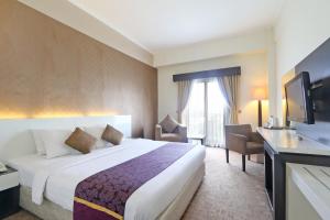 una camera d'albergo con un letto e una TV a schermo piatto di Hotel Kaisar a Giacarta