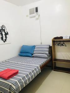Queen's Room Rental 3 في إل نيدو: سرير مع وسائد زرقاء وحمراء في الغرفة