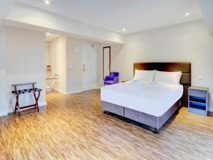 a bedroom with a large white bed and a blue chair at OYO The Gissons Hotel in Exeter