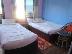 a room with two beds and a table and a window at STUPA VIEW INN in Kathmandu +236 photos