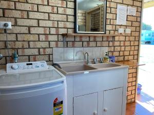 a kitchen with a sink and a brick wall at Leander Reef Holiday Park in Port Denison