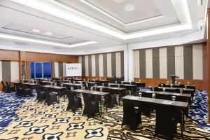 a conference room with tables and chairs and a screen at ASTON Inn Cilacap in Cilacap