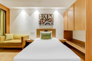 a hotel room with a bed and a chair at Lemon Tree Hotel, Ahmedabad in Ahmedabad