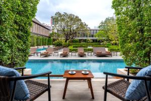 a patio with chairs and a table next to a pool at Villa Deva Resort & Hotel Bangkok in Bangkok