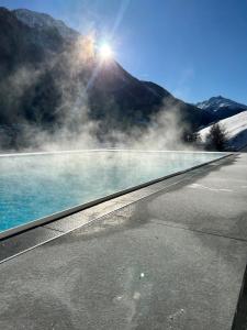 a pool of water with a mountain in the background at Hotel Zalwonder in Ischgl