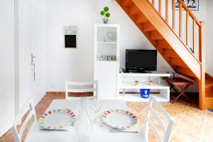 a white dining room with a white table and a tv at Appartement au pays basque in Ahetze
