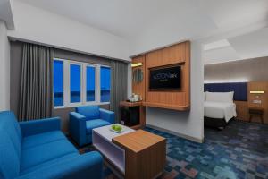 a hotel room with a blue couch and a bed at ASTON Inn Cilacap in Cilacap
