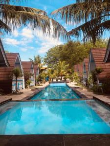 a large blue swimming pool with palm trees and houses at Youpy Bungalows in Gili Air
