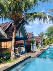 a house with a palm tree next to a swimming pool at Youpy Bungalows in Gili Air