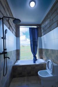 a bathroom with a tub and a toilet and a window at Amboseli Cultural Camping in Amboseli