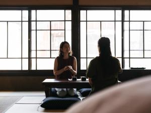 two women sitting at a table in a room with windows at RITA Yame Fukushima in Yame