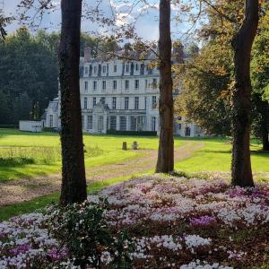 a white house with trees and flowers in front of it at Les Ecuries du Château de Brumare in Brestot