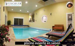 a swimming pool in a room with chairs at L'Escale Evel Er Gêr in Locquirec