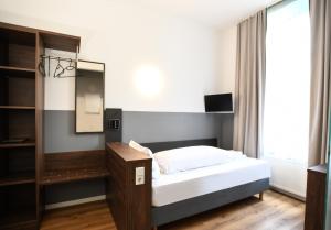 a small bedroom with a bed and a mirror at Hotel Apadana Frankfurt in Frankfurt/Main