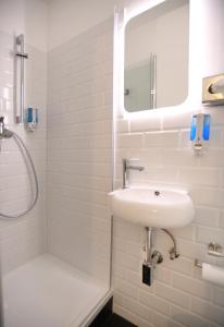 a white bathroom with a sink and a shower at Hotel Apadana Frankfurt in Frankfurt/Main