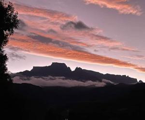 een zonsondergang met een berg in de lucht met wolken bij Mountain Splendour Eco Resort in Winterton