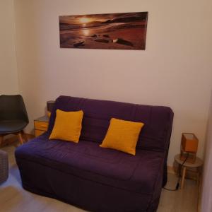ラ・トランシュ・シュル・メールにあるLa commanderieの紫色のソファ(黄色の枕付)が備わるリビングルームです。