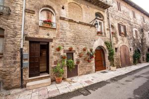 - un bâtiment en pierre avec des portes et des plantes en pot dans l'établissement Residenza Vicolo Bovi Assisi, à Assise