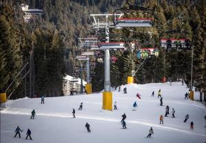 a group of people skiing down a snow covered slope at Апартамент B9 in Borovets