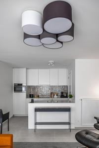 una cocina con armarios blancos y una gran lámpara de araña en Casselbergh Residences Petunia - De Haan, en De Haan