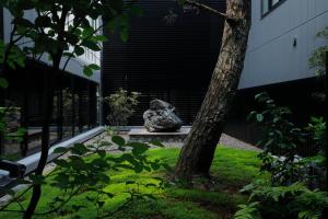 uma pedra sentada num banco ao lado de uma árvore em hotel tou nishinotoin kyoto em Quioto