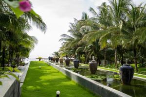 uma fileira de palmeiras e um corpo de água em Sonata Resort & Spa em Phan Thiet