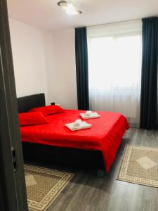 Un dormitorio con una cama roja con dos toallas encima. en Ilinca-ZGATIA, en Piatra Neamţ