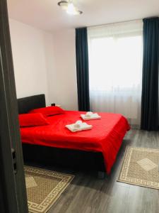 a bedroom with a red bed with two towels on it at Ilinca-ZGATIA in Piatra Neamţ