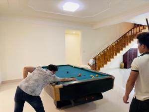 dos hombres jugando al billar en una habitación en Dalat Eco House en Trai Mat