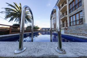 a swimming pool in front of a building with a palm tree at Apartagal-Mar de Vicedo in O Vicedo
