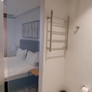 a small bedroom with a bed and a shower at 117 on Strand - Luxury Apartments in Cape Town