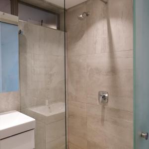a bathroom with a shower with a glass door at 117 on Strand - Luxury Apartments in Cape Town