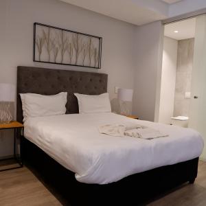 a bedroom with a large bed with white sheets at 117 on Strand - Luxury Apartments in Cape Town
