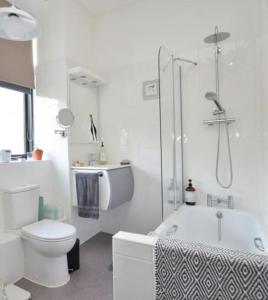 y baño blanco con ducha y aseo. en Philippa Court Grade II townhouse- 3 bedrooms- free parking, en Norwich